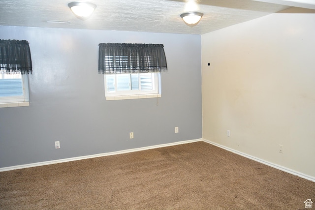 carpeted empty room featuring baseboards and a textured ceiling