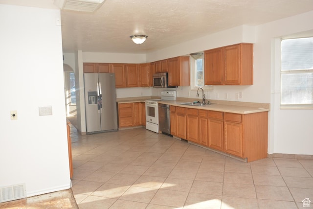 kitchen with a textured ceiling, visible vents, light countertops, appliances with stainless steel finishes, and a sink