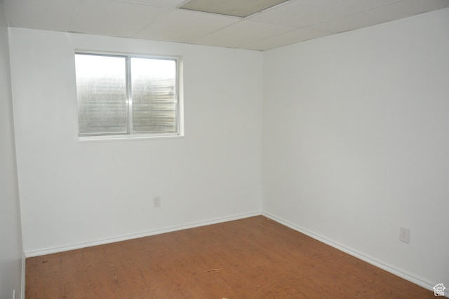 spare room featuring baseboards, wood finished floors, and a paneled ceiling