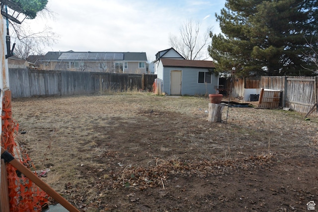 view of yard featuring a fenced backyard, an outdoor structure, and a storage shed