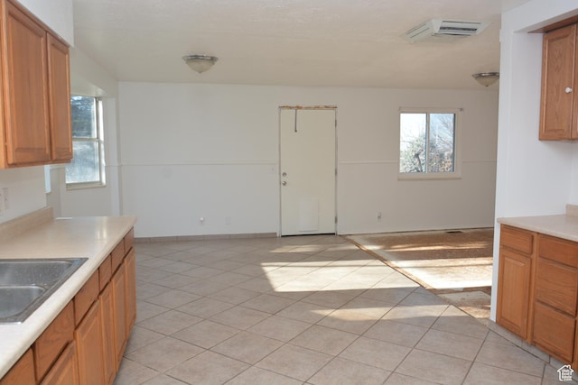 kitchen with light countertops, a sink, light tile patterned floors, and a wealth of natural light