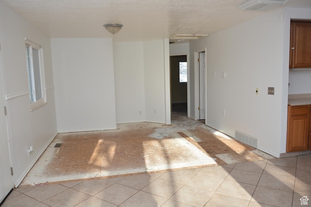 spare room with a textured ceiling, visible vents, and light tile patterned floors