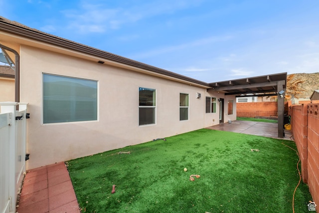 rear view of house featuring a lawn, a patio area, a fenced backyard, and stucco siding