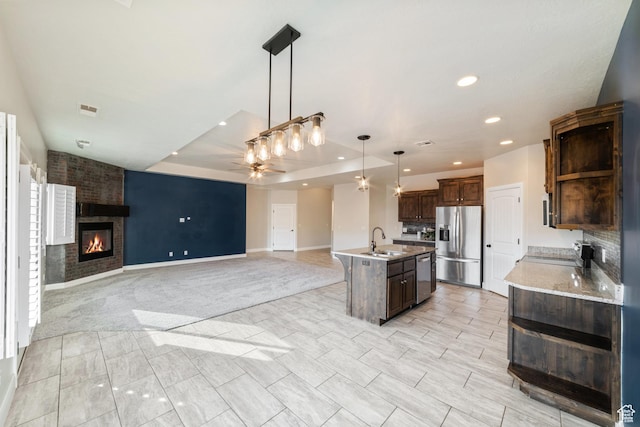 kitchen with a fireplace, a sink, visible vents, open floor plan, and appliances with stainless steel finishes