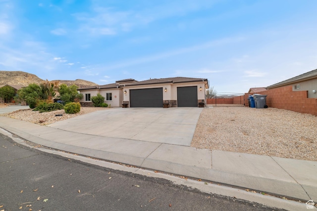 view of front of home with an attached garage, fence, driveway, a gate, and stucco siding