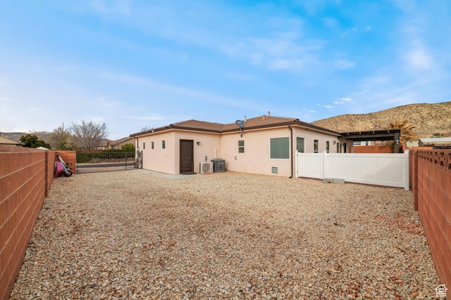 rear view of property with cooling unit, a fenced backyard, and stucco siding