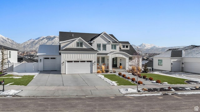 view of front of house with concrete driveway, a mountain view, board and batten siding, and fence