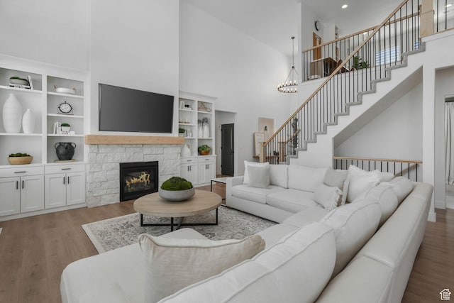 living area with stairway, wood finished floors, a towering ceiling, and a fireplace