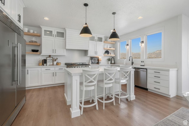 kitchen featuring light wood finished floors, a center island, open shelves, and stainless steel appliances