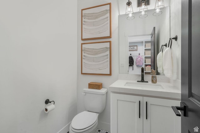 half bath with vanity, baseboards, and toilet