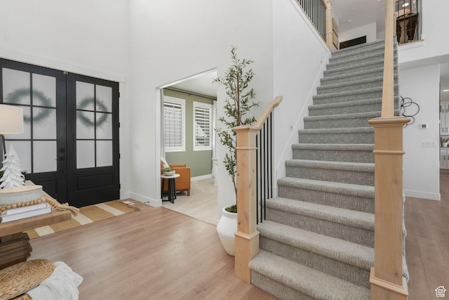 foyer entrance featuring wood finished floors, a towering ceiling, baseboards, and stairway
