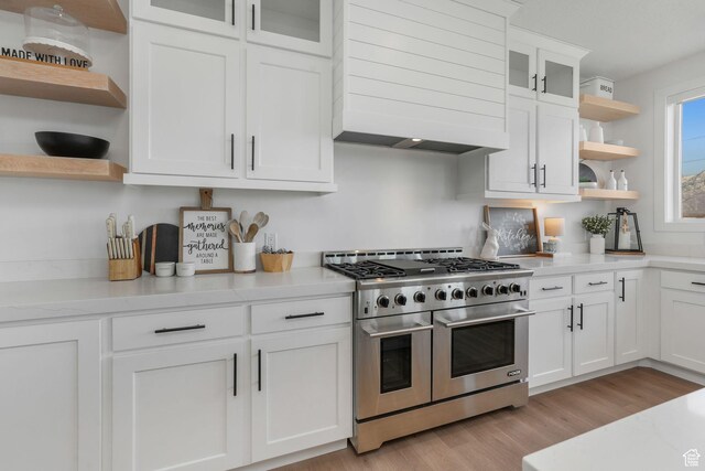 kitchen featuring premium range hood, range with two ovens, light countertops, and open shelves