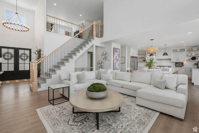 living area featuring light wood-style flooring, a high ceiling, and stairs