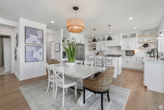 dining room with baseboards, light wood-type flooring, an inviting chandelier, and recessed lighting