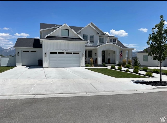 view of front of property with a front yard, a porch, board and batten siding, fence, and driveway
