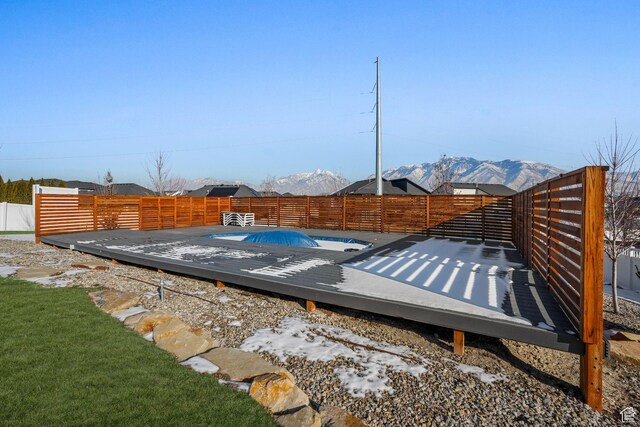 view of swimming pool featuring a deck with mountain view and a fenced backyard