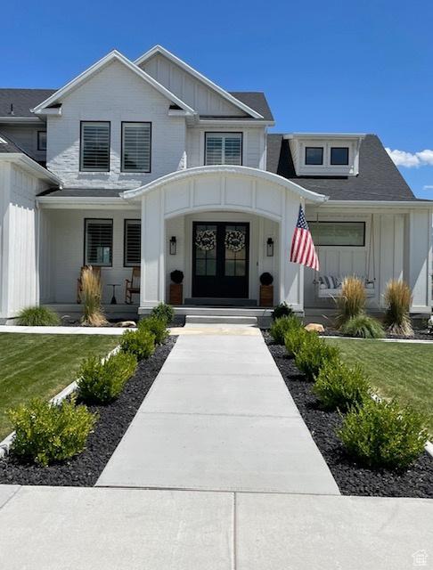 property entrance with board and batten siding, a porch, and a lawn