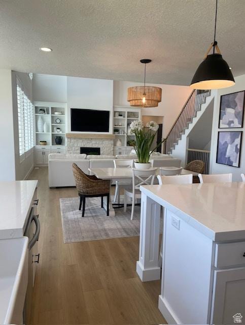 kitchen featuring decorative light fixtures, a textured ceiling, light wood finished floors, and light countertops