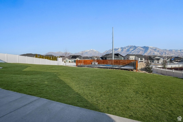 view of yard featuring a mountain view, a fenced backyard, and a residential view