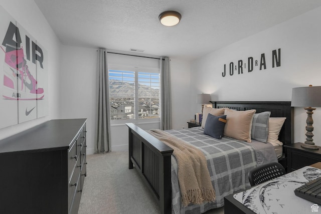 bedroom with baseboards, visible vents, light colored carpet, and a textured ceiling