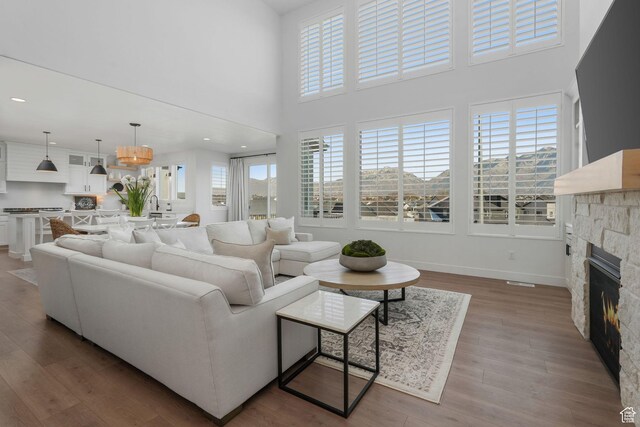 living room featuring a high ceiling, wood finished floors, a fireplace, and baseboards