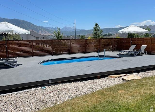 view of pool featuring a deck with mountain view and a fenced backyard