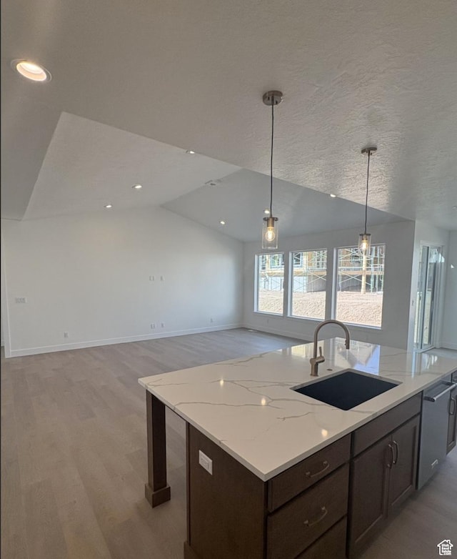 2387 E Canyon Crest Dr Unit 44, Spanish Fork, UT 84660 - kitchen with decorative light fixtures, light wood-style flooring, a kitchen island with sink, vaulted ceiling, and a sink