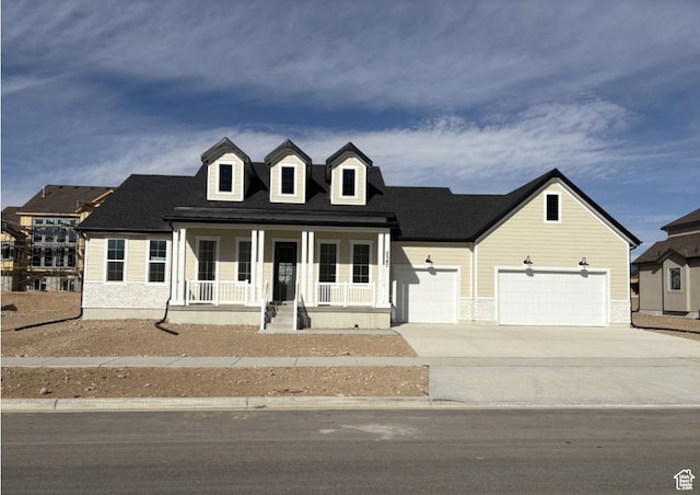cape cod house with covered porch, driveway, and an attached garage
