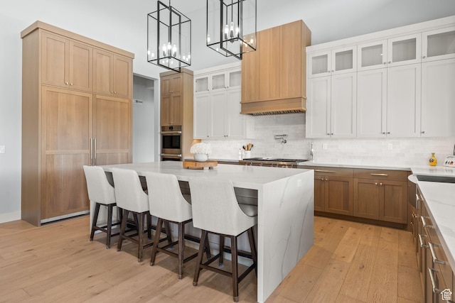 2344 Nighthawk Cir, Park City, UT 84098 - kitchen featuring a center island, tasteful backsplash, glass insert cabinets, light wood-type flooring, and a kitchen bar