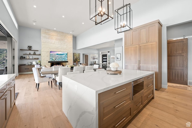 2344 Nighthawk Cir, Park City, UT 84098 - kitchen with a stone fireplace, stainless steel microwave, a towering ceiling, and light wood-style floors