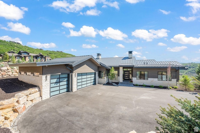 2344 Nighthawk Cir, Park City, UT 84098 - contemporary house featuring driveway, a chimney, metal roof, an attached garage, and a standing seam roof