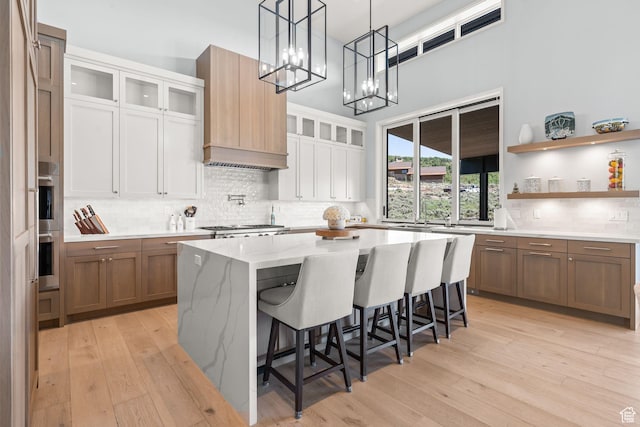 2344 Nighthawk Cir, Park City, UT 84098 - kitchen featuring decorative backsplash, light stone counters, custom exhaust hood, light wood-type flooring, and a kitchen bar