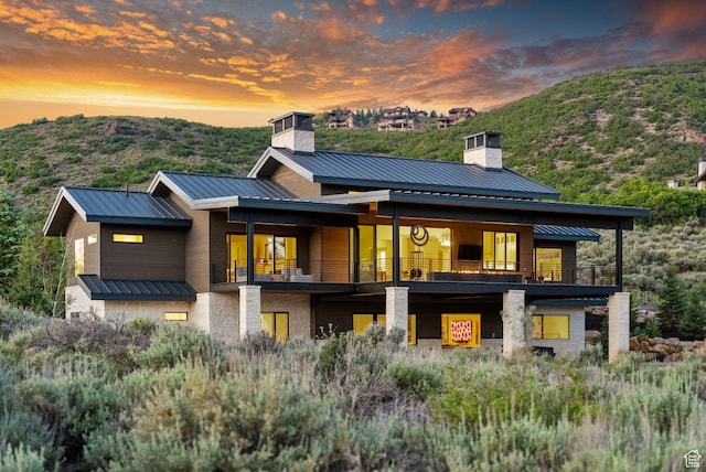 2344 Nighthawk Cir, Park City, UT 84098 - back of property at dusk featuring a chimney, a standing seam roof, metal roof, a balcony, and a mountain view