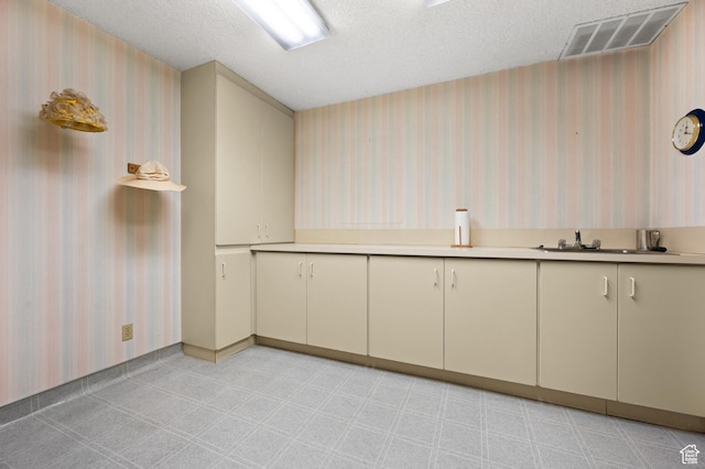 3604 S Crestwood Dr, Salt Lake City, UT 84109 - kitchen featuring light countertops, visible vents, cream cabinets, a textured ceiling, and wallpapered walls