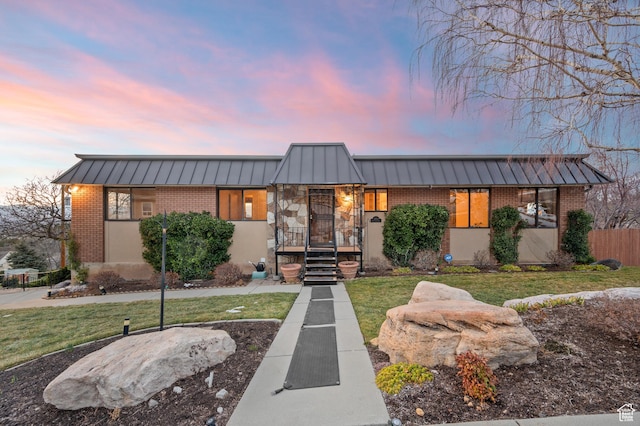 mid-century inspired home with a standing seam roof, brick siding, metal roof, and a front lawn