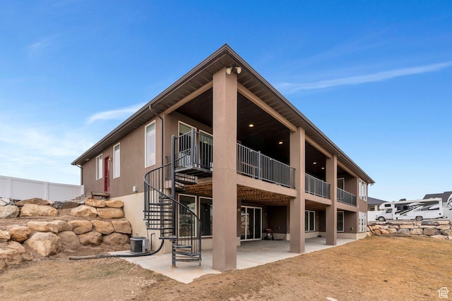 1407 E Abigail Ln, Eagle Mountain, UT 84005 - rear view of house featuring stucco siding, stairway, central AC, and a patio