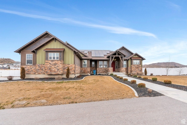 1407 E Abigail Ln, Eagle Mountain, UT 84005 - craftsman-style home featuring solar panels, board and batten siding, a mountain view, fence, and stone siding