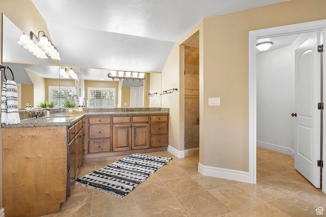 bathroom featuring a walk in shower, lofted ceiling, vanity, and baseboards