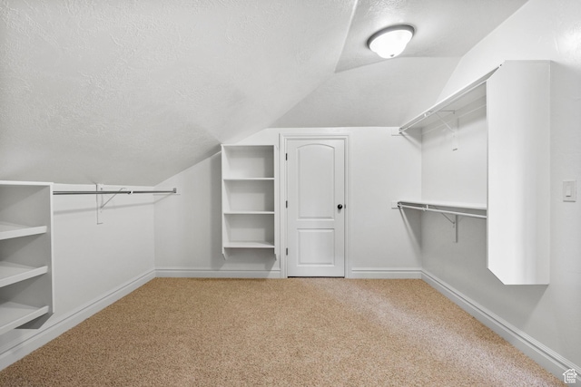 walk in closet with vaulted ceiling and carpet