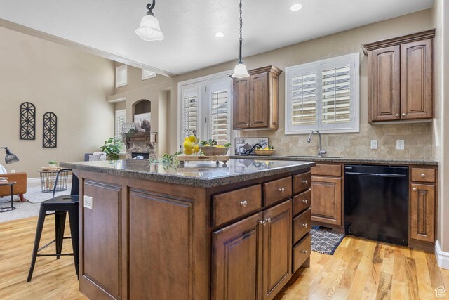 kitchen with decorative backsplash, dishwasher, a center island, light wood-type flooring, and a sink