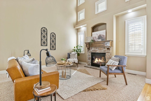 living room featuring a fireplace, visible vents, a high ceiling, wood finished floors, and baseboards