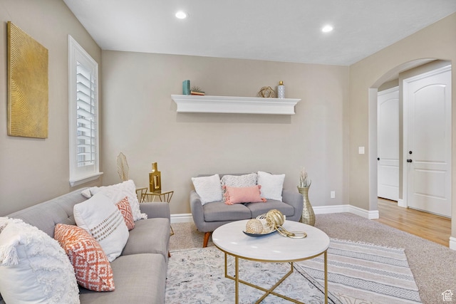 carpeted living area featuring baseboards, arched walkways, and recessed lighting