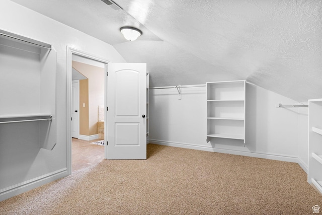 spacious closet with lofted ceiling, visible vents, and light colored carpet