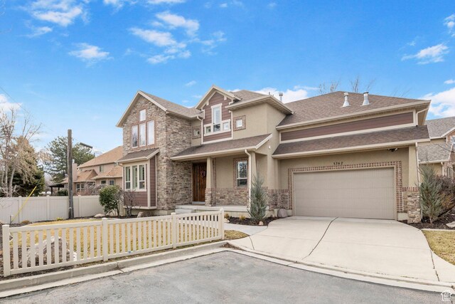 view of front of home featuring a fenced front yard, stucco siding, concrete driveway, a garage, and stone siding