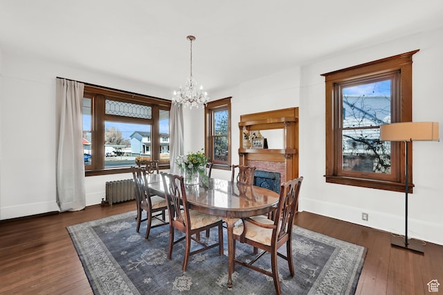 dining area with radiator heating unit, wood finished floors, an inviting chandelier, and baseboards