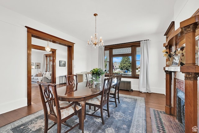 dining space featuring radiator, radiator heating unit, a chandelier, wood finished floors, and baseboards