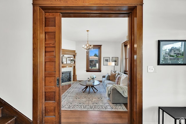 living room with an inviting chandelier, wood finished floors, and a fireplace with flush hearth