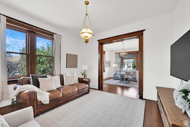 living area with a chandelier, baseboards, and dark wood-style floors
