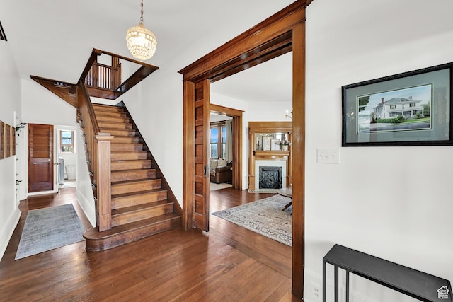 stairs featuring a fireplace, a notable chandelier, and hardwood / wood-style floors