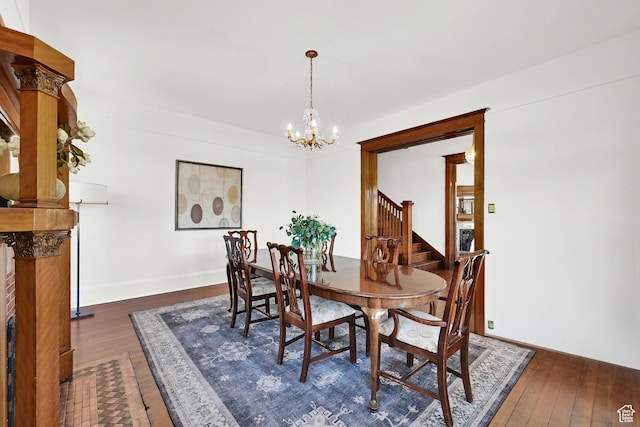 dining room featuring dark wood-style flooring, an inviting chandelier, baseboards, and stairway